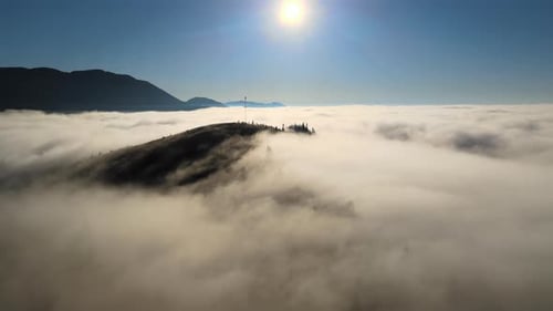 Luftbild des farbenfrohen Sonnenaufgangs über weißem, dichtem Nebel mit fernen dunklen Silhouetten von Berghügeln