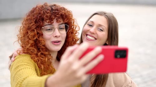 Two Smiling Women Taking Selfie Outdoors