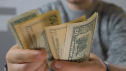 Mãos masculinas irreconhecíveis contando notas de denominação em dólares americanos e oferecendo dinheiro