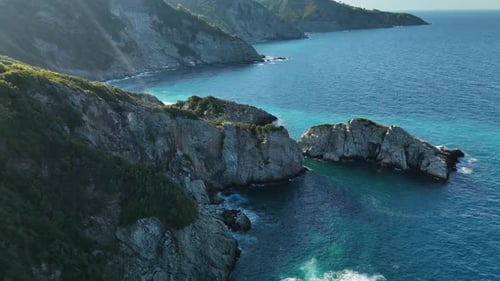 Rugged coastal cliffs and turquoise sea water during a sunny day, aerial view