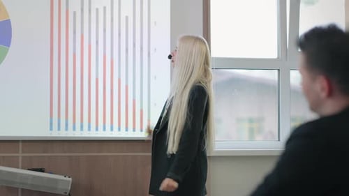 Una entrenadora de negocios está demostrando y comentando diagramas y gráficos en una reunión de negocios