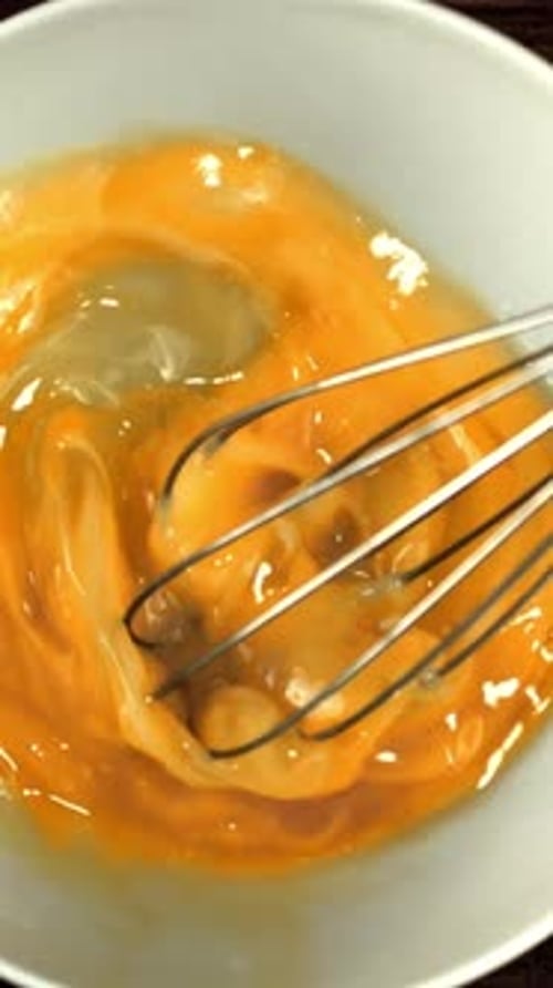 Super Slow Motion the Man's Hand Stirs the Raw Egg with a Whisk Filmed on a Highspeed Camera at 1000