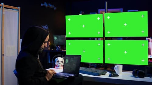 Un hacker usa la computadora y el portátil Chroma Key para crear scripts de malware