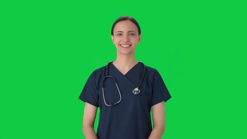 Happy Indian female doctor putting stethoscope on Green screen