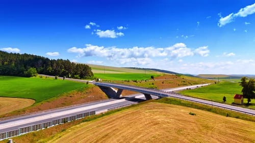 Approaching the bridge with road over the highways. Vast fields are around the roads.