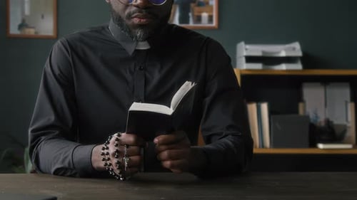Adult Reading Religious Book Holding Rosary Indoors
