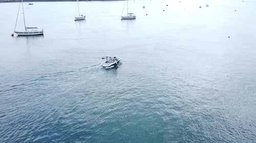 Leisure motor boat aerial view navigating quiet river Conwy harbour marina between yachts