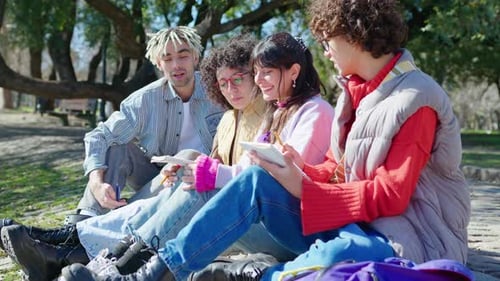 Cheerful College Friends Sitting in the Park and Doing Homework