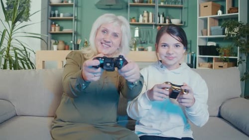 Grandmother and Granddaughter Playing Video Games on Couch