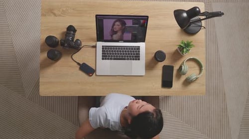 Vista superior de una editora asiática que tiene dolor de espalda mientras usa una computadora portátil editando una foto