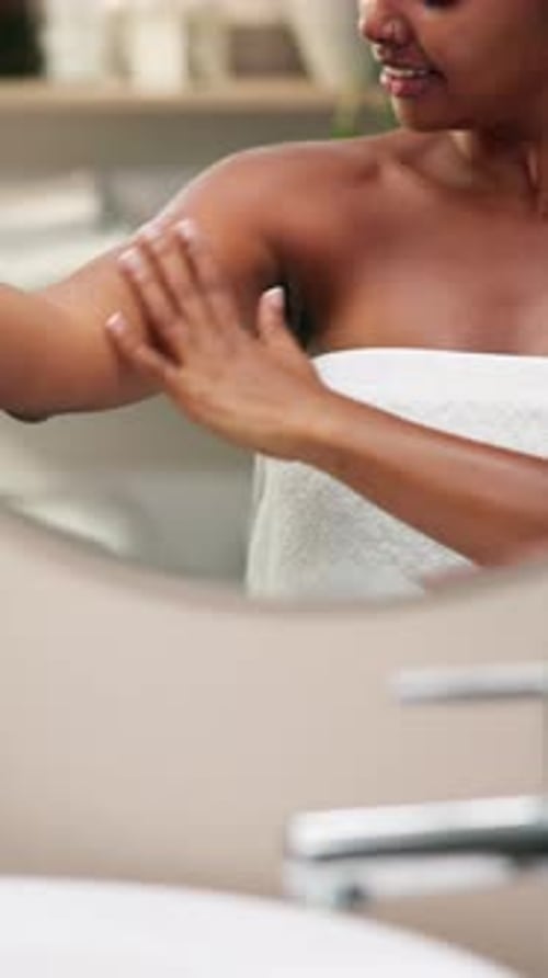 Hands, lotion and shoulder with skincare by mirror in bathroom for smooth texture