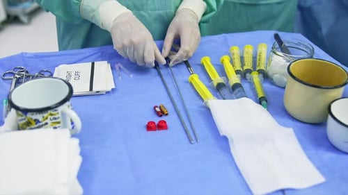 Hands of medic in latex gloves touching tools on the table.