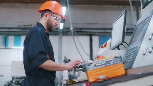 Bedienung der Maschine. Der Fabrikarbeiter ist mit Schutzhelm drinnen.