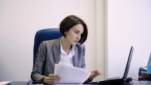 A Professional Woman Engaging in the Detailed Analysis of Important Documents in an Office Setting