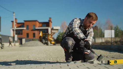 Young Man Laying Paving Stones with Mallet