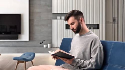 Man Reading Book on Sofa Indoors
