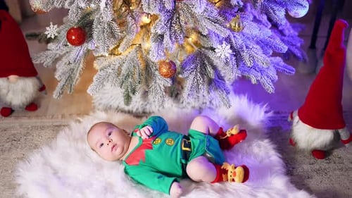 Caucasian child in green elf costume and red socks with deer resting on the fluffy plaid.