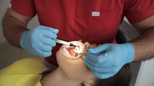 A Professional Dentist Performs a Teeth Whitening Procedure Beautiful Smile