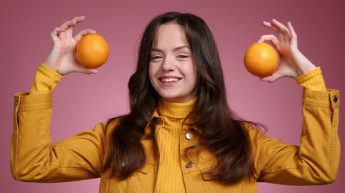 Cheerful Woman Holds Oranges in Studio Setting