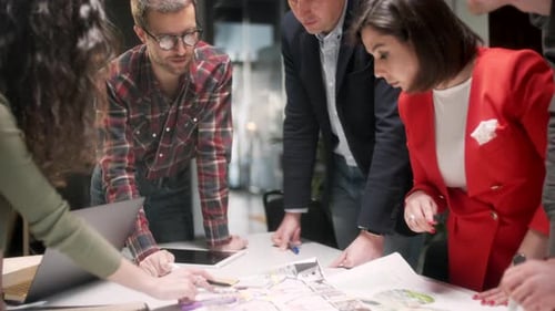 Colleagues And Clients Talking Strategy With Project Blueprint In Creative Office Productive