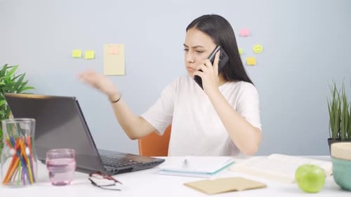 Woman Talking on Phone While Using Laptop