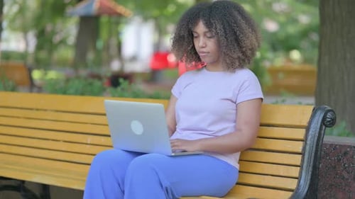 Woman Using Laptop on Park Bench Smiling