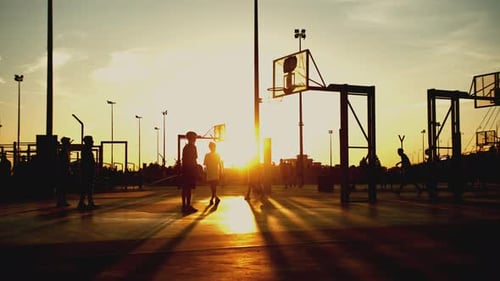 Silhouette Basketball Players in Golden Sunlight at Sunset