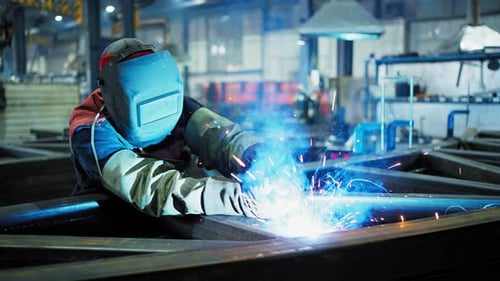 Professional Welder Working at Factory Facility Factory Workshop with a Male Technician Welding in