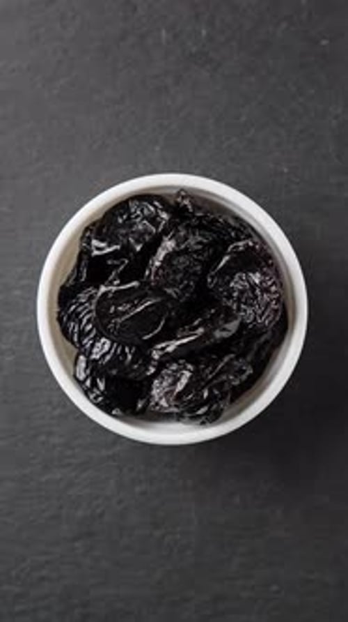 Bowl of Prunes on Black Stone Slate Rotating Vegetarian Nutrition Dried Fruit