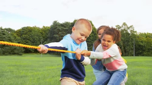 Concepto de infancia, ocio y personas: grupo de niños felices jugando al tira y afloja