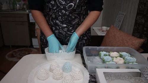 Woman Dusting White Desserts With Powder in Kitchen