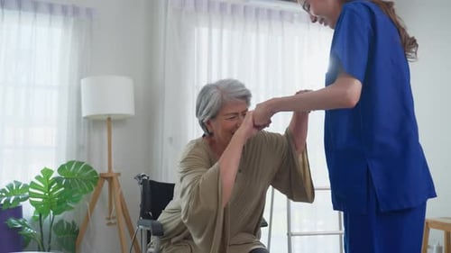 Nurse Helping Senior Woman Stand from Wheelchair