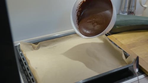 Frau gießt Schokoladen-Brownie-Teig aus der Schüssel in ein Backblech - Zoomt zur Nahaufnahme