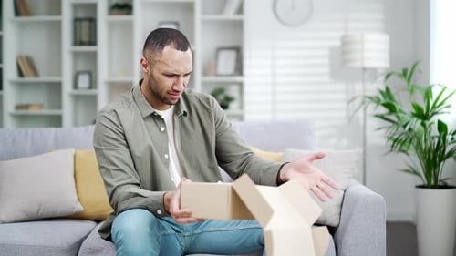 Man Opens Box and Reacts with Surprise