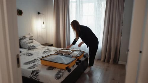 Menina colocando roupas em uma mala