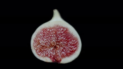 Half of a ripe and juicy Fig with red pulp, rotating on a black background. Isolated for cutting out