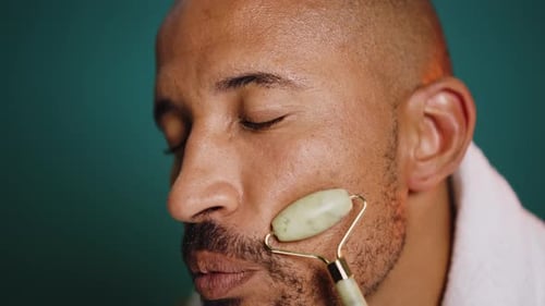 Man Massaging Face With Facial Jade Roller