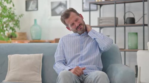 Man Massaging Stiff Neck in Living Room