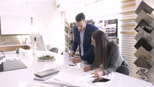 Of Interior Designers Working on Blueprint in Showroom