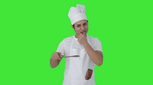 Happy Indian professional chef tasting good food Green screen