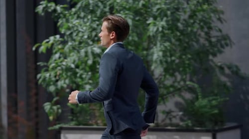 Serious businessman running late for important meeting in modern office yard