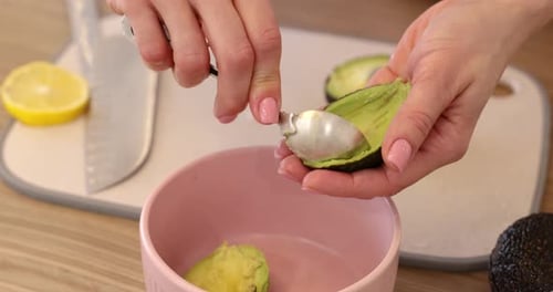 Woman Prepares Avocado With Spoon in Kitchen