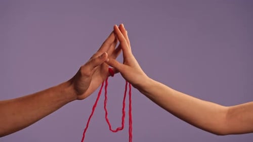 Man and Woman Hands Touching Tied Connected with Red Thread on Fingers Isolated on Purple Studio