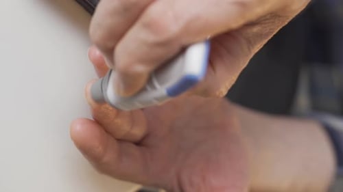 Vídeo vertical de close-up de um velho medindo o açúcar no sangue.