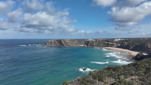 Long aerial shot flying over a beautiful coastal area with hills, cliffs and a secluded bay
