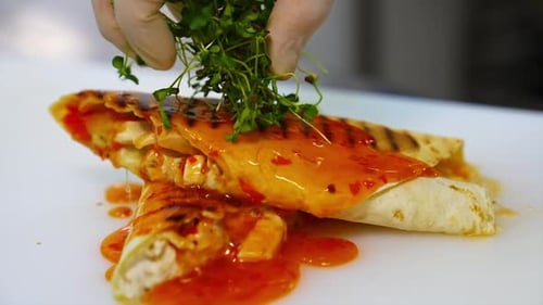 Delicious pita poured with sauce. Cook decorates a dish with green sprouts.