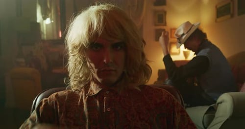 Cinematic shot of young homosexual male gay is taking off wig and smiling in camera on a backgroun