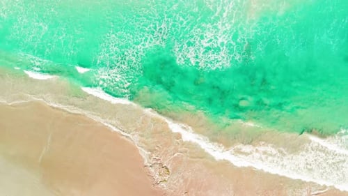 Areal top view video sequence of waves closing to coastline, crystal clear sea water splashing on sa