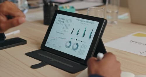 Hands Analyzing Reports on Tablet at Meeting