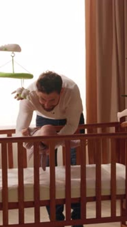 Bearded Adult Lifts Baby from Wooden Crib